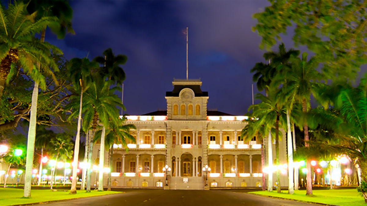 night view of Iolani Palace with lights and palm tress in Oahu, Hawaii, USA