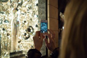 woman taking photo of bergdorf goodman holiday window display