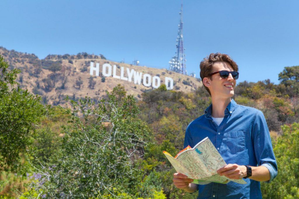 man with map standing in front of hollywood sign