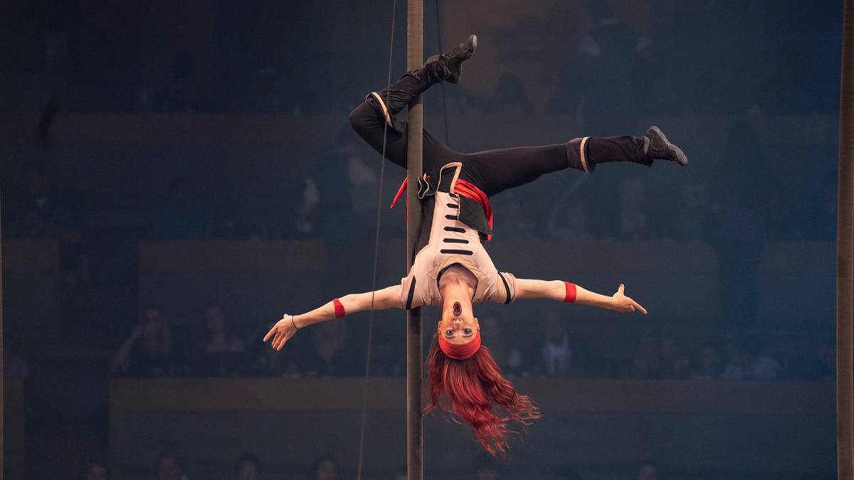 Female pirate with red hair hanging upside down with one of her legs wrapped around a pole at the Pirates Voyage Dinner and Show in Myrtle Beach, South Carolina, USA
