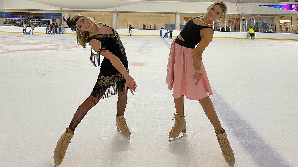 Two young women in ice skates posing for a photo with their arms out in costumes at The Rink in the American Dream Mall in Rutherford, New Jersey, USA