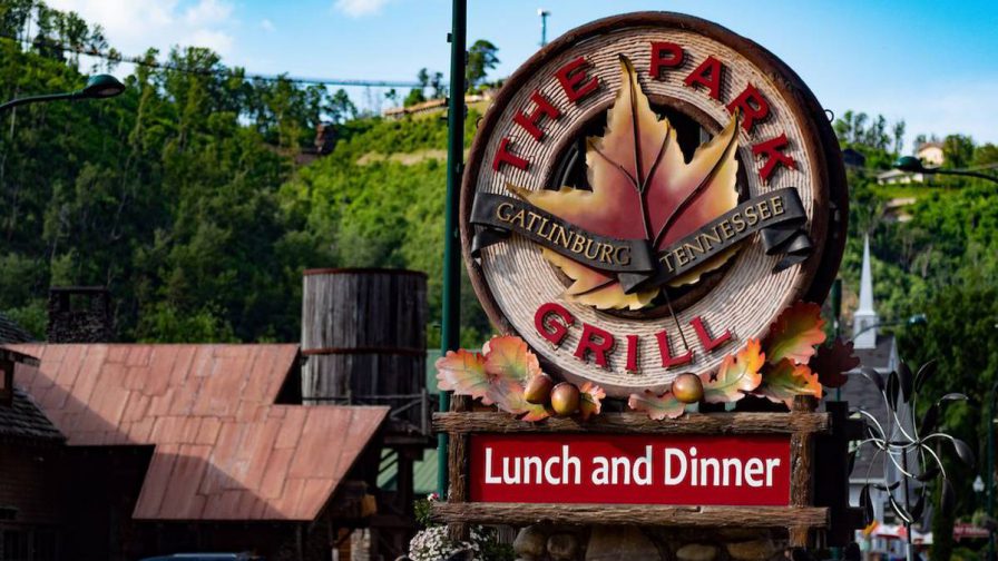 Close up of a sign with a large leaf on it for The Park Grill with trees in the background in Gatlinburg, Tennessee, USA