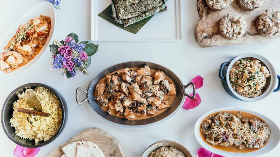 Looking down at a white table full of different dishes at 53 By The Sea in Honolulu, Hawaii, USA
