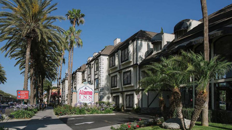 View looking down the Alamo Inn and Suites and a side walk lined with palm trees on a sunny day in Los Angeles, California, USA