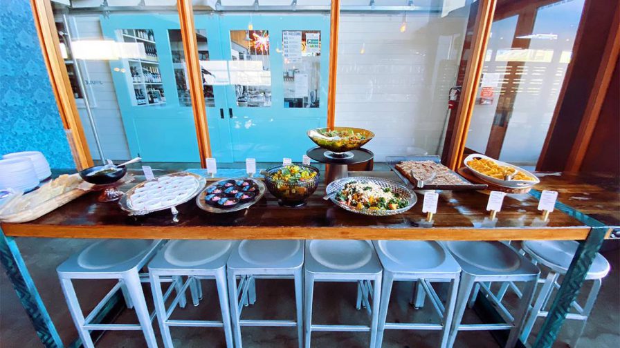 A long table filled with food with white stools under it and windows behind it Joule in Seattle, Washington, USA