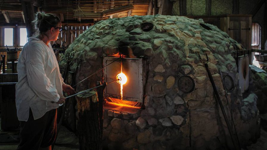Woman in a white shirt heating glass at the Glasshouse in Jamestown near Williamsburg , Virginia, USA