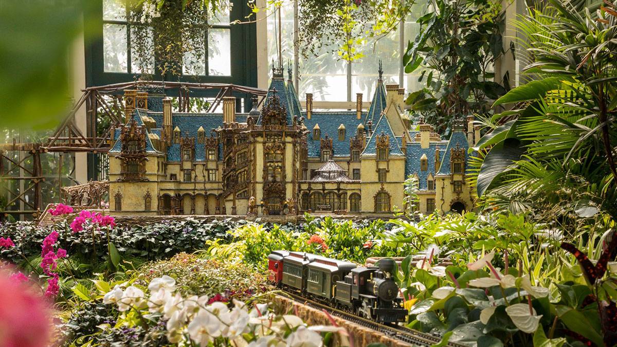 miniature model of the Biltmore estate with model train in the foreground surrounded by various plants and flowers in Biltmore Gardens Railway, Asheville, North Carolina, USA