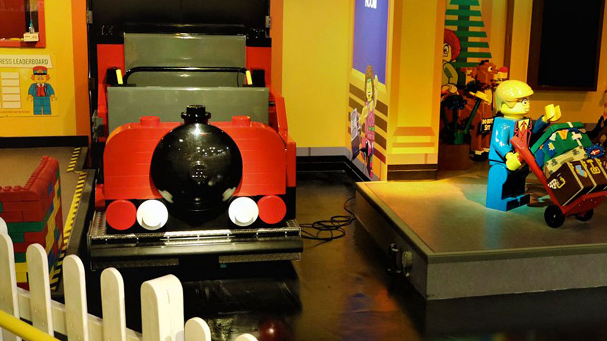 close up of Imagination Express ride at Legoland Discovery Center with lego character figures at the side and white fence in the foreground in Philadelphia, Pennsylvania, USA