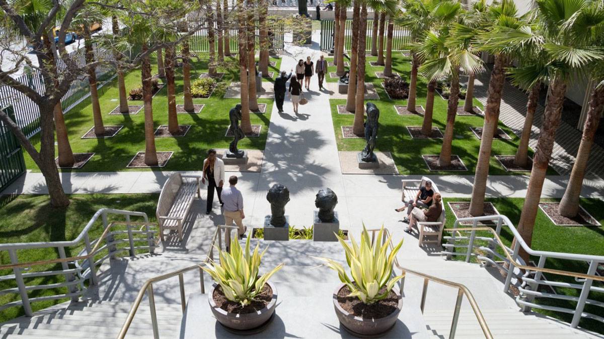 people walking along the LACMA (Los Angeles County Museum of Art) B. Gerald Cantor Sculpture Garden filled with trees and sulptures in Los Angeles, California, USA