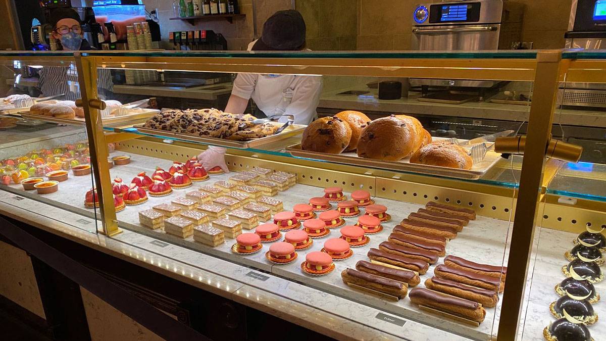 close up of pastries in display case for sale with chefs behind counter at Les Halles Boulangerie-Patisserie in Epcot, Disneyworld, Orlando , Florida, USA