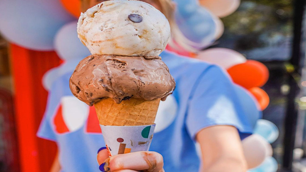 woman holding cone of ice cream with two scoops at Odd Fellows Ice Cream Co in Tampa, Florida, USA