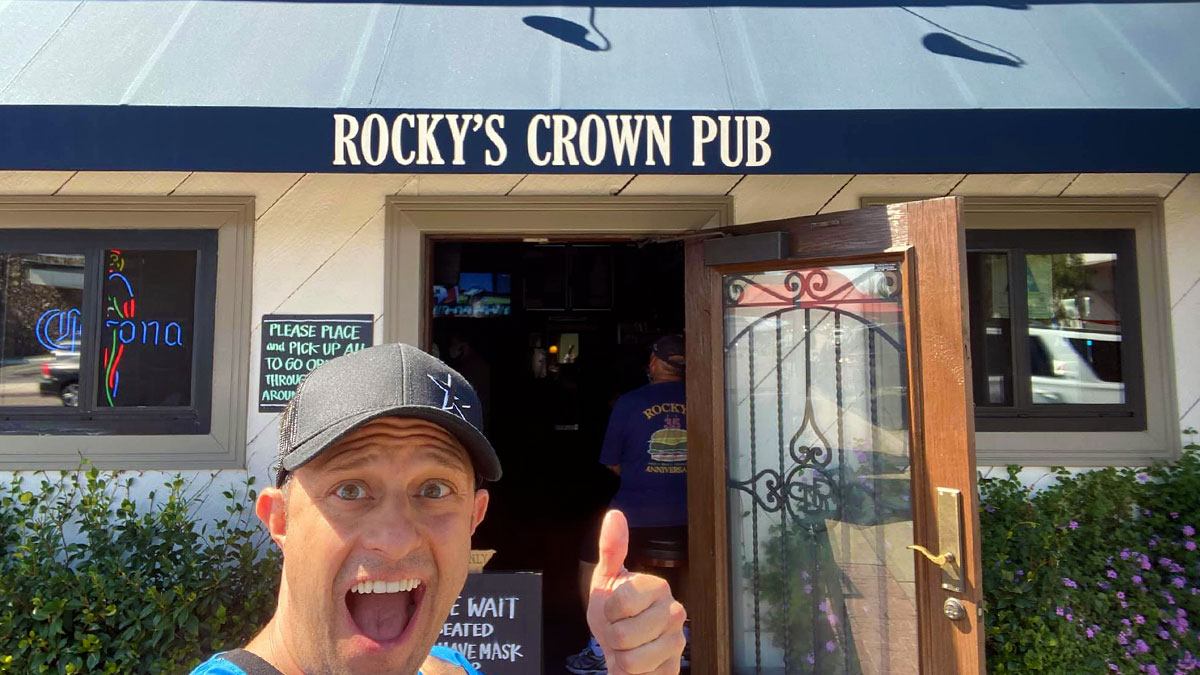 man with excited expression holding up thumbs up sign posing in front of Rocky's Crown Pub entrance at Rocky's Crown Pub in San Diego, California, USA