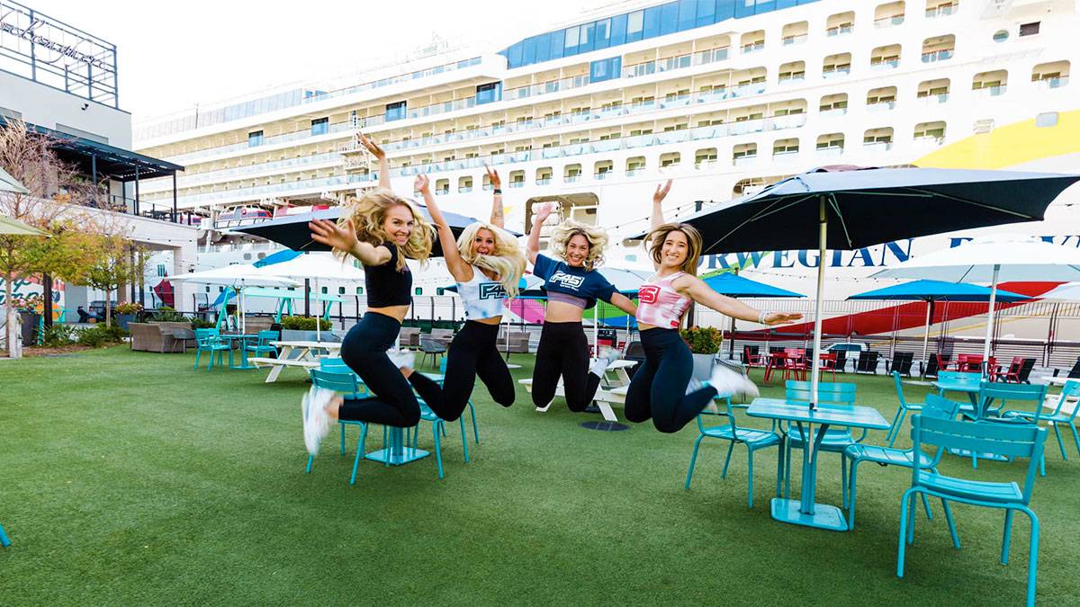group of women in athletic wear jumping with colored chairs and umbrellas in background in Sparkman Warf Tampa, Tampa, Florida, USA