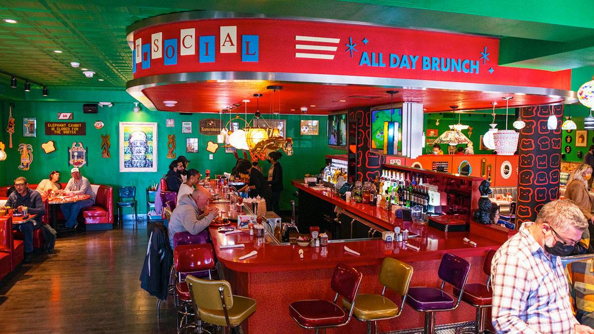 people dining at The Friendly Toast restaurant with booths, tables, and chairs, decorated in red and green color scheme in Boston, Massachusetts, USA