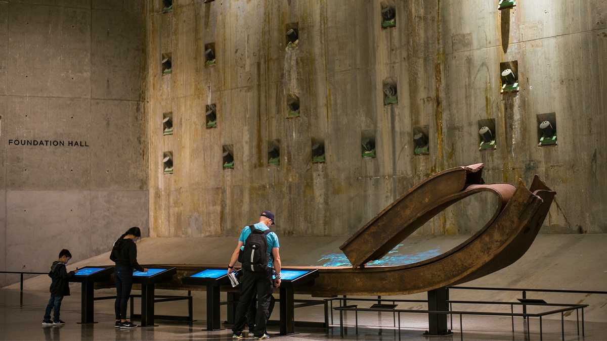 Three people looking at the interactive Signing Steel exhibit at the National September 11 Memorial & Museum in NYC, New York, USA