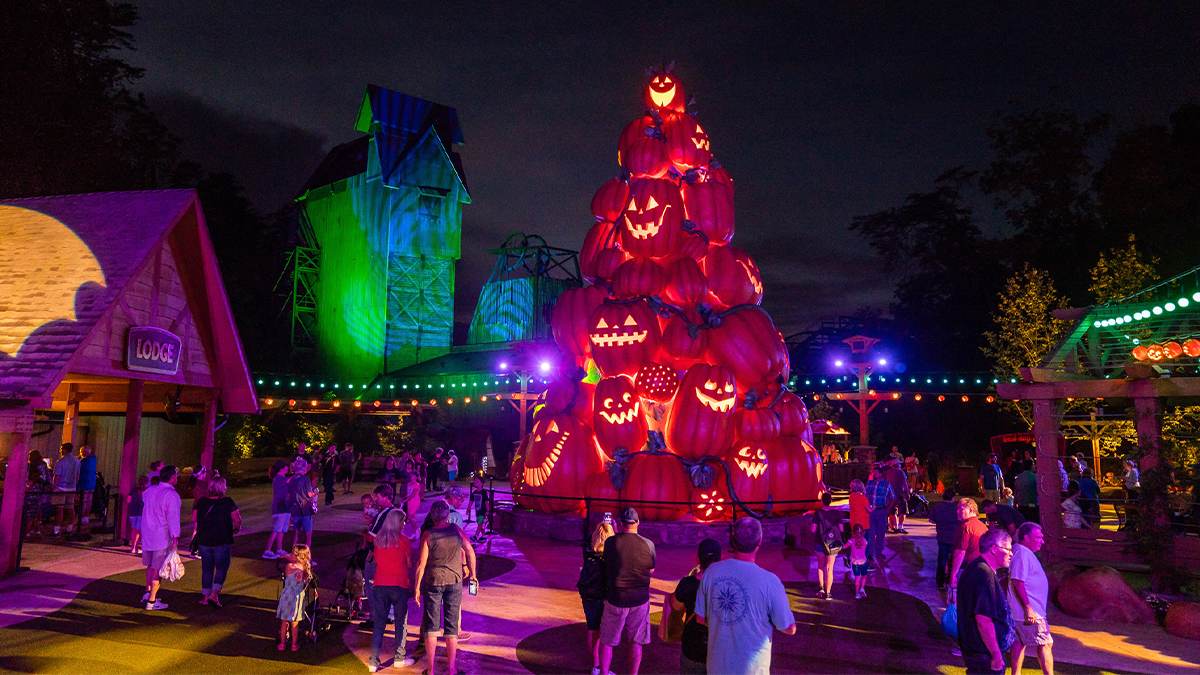 People gathered around the Pumpkin Tree at Harvest Celebration, a tower of jack-o-lanterns a glow in the middle of a courtyard at Dollywood in Pigeon Forge, Tennessee, USA