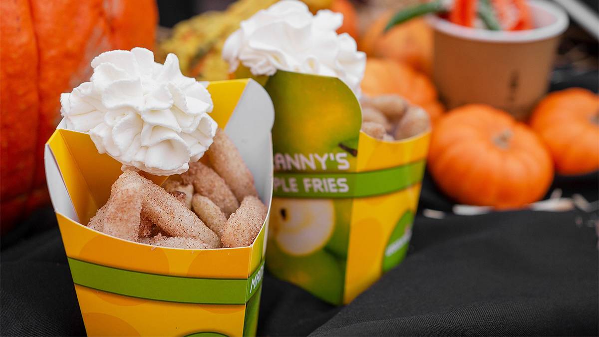 Close up photo of a serving of Granny's Apple Fries in a green and yellow container with whipped cream at LEGOLAND in San Diego, California, USA