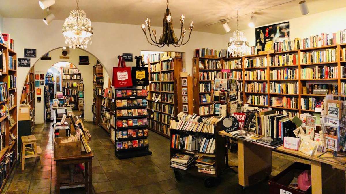 View of the interior of Adobe Books with lots of shelves on the wall and tables in the middle of the room plus arched doorways in San Francisco, California, USA