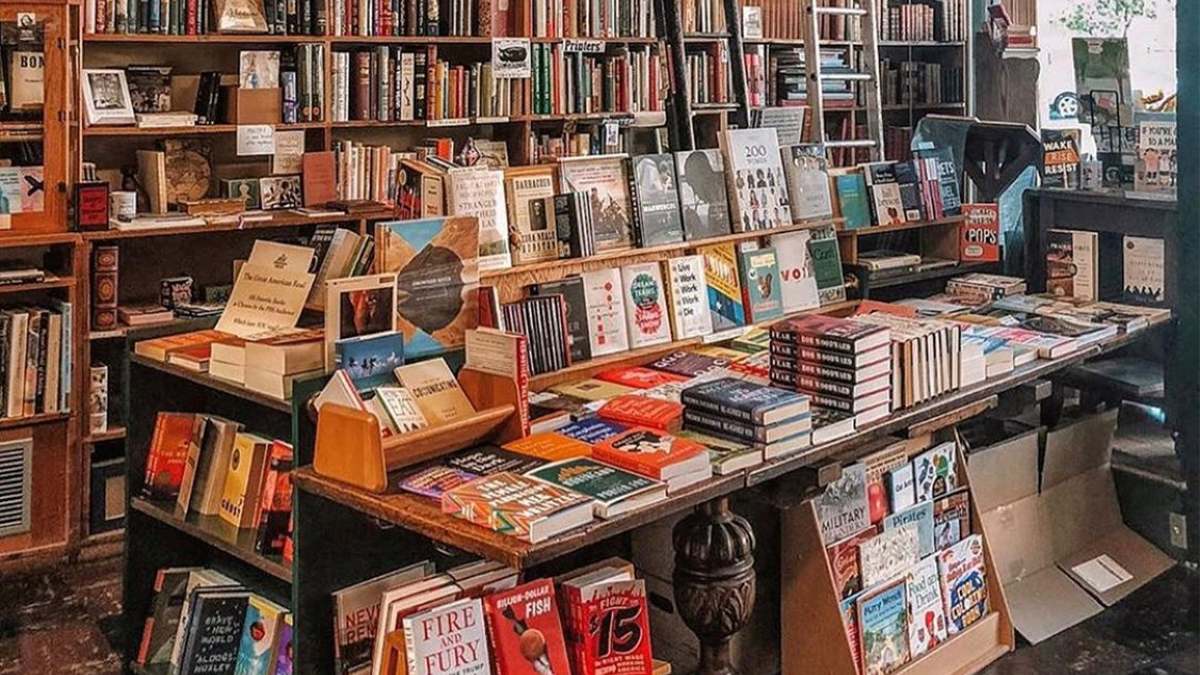 Close up of a large book display with several stacks of books and a shelf full behind it at Bell’s Books Palo Alto near San Francisco, California, USA