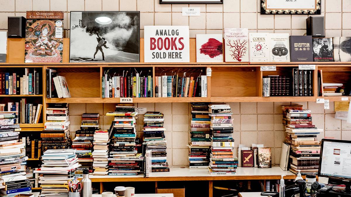 View of the interior of Moe’s Books, stacks of books piled everywhere and books on a wooden shelf on the wall in San Francisco, California, USA